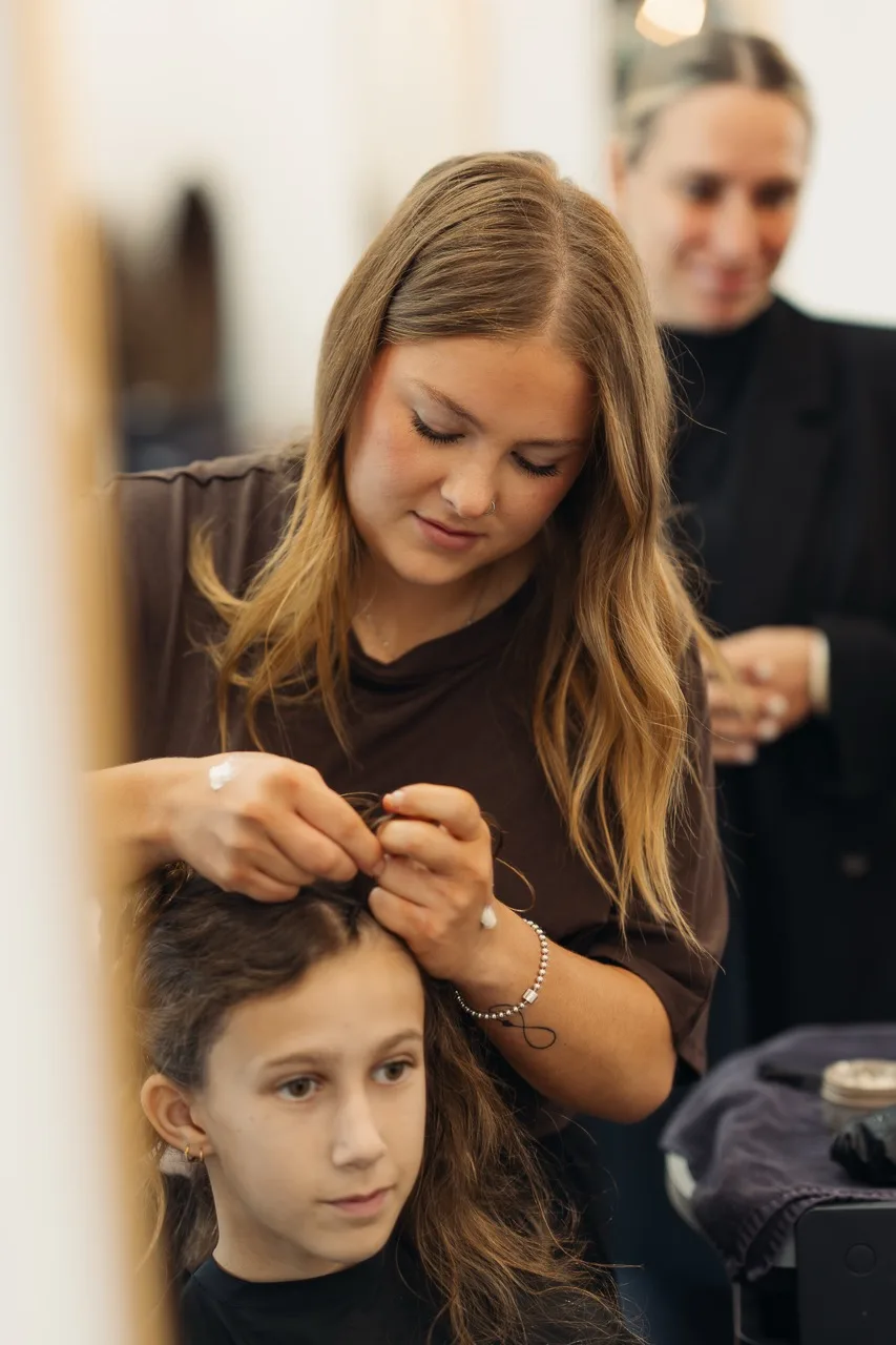 A Linea stylist braiding a young client’s hair